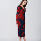 Side profile of the model in V-neck red and navy midi dress showing sleeve length and silhouette.
