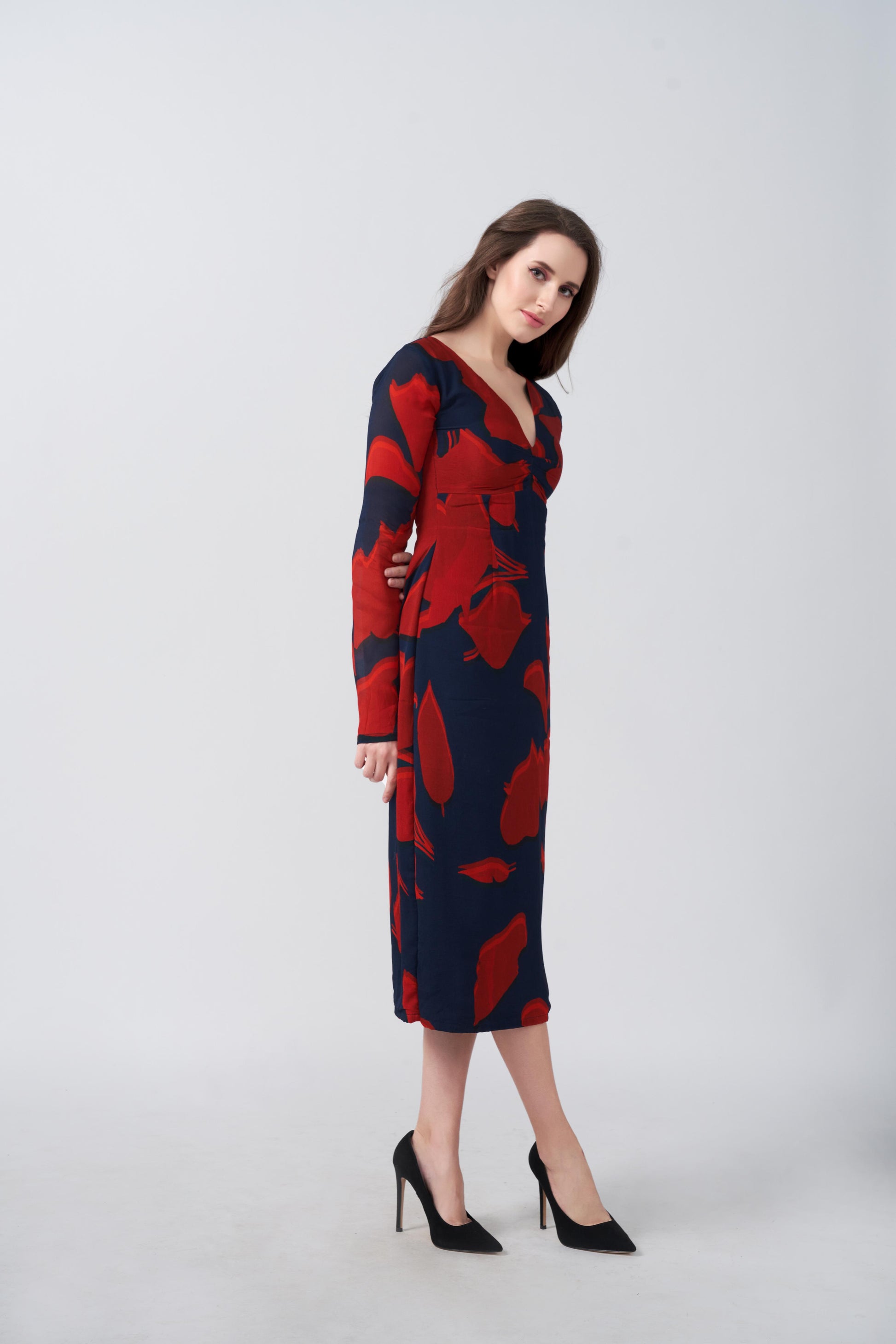 Side profile of the model in V-neck red and navy midi dress showing sleeve length and silhouette.