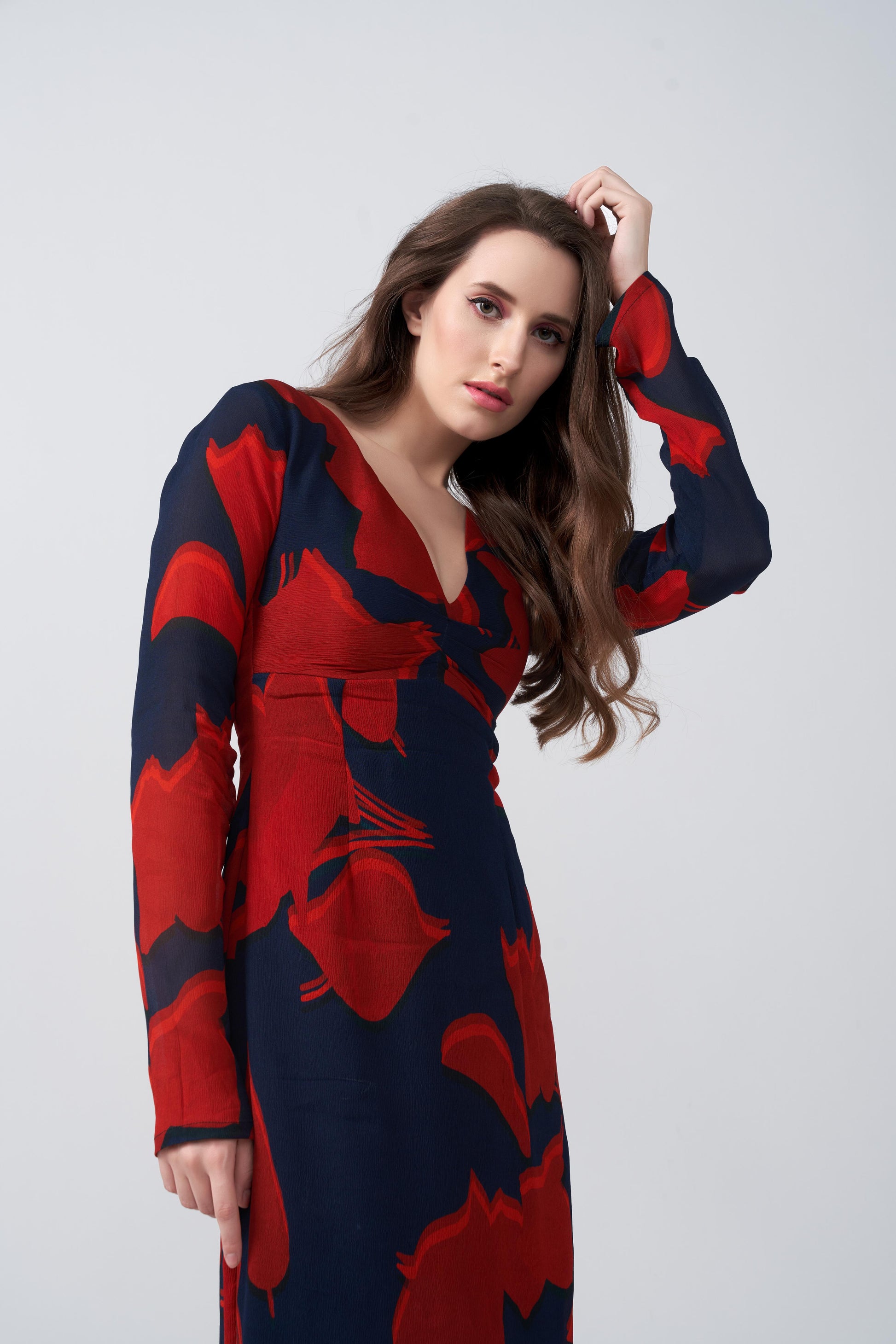 Close up view of the model highlighting movement and flow of the long-sleeved red floral dress.
