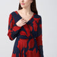 Close-up front view of model wearing red and navy abstract chinon dress with V-neckline.