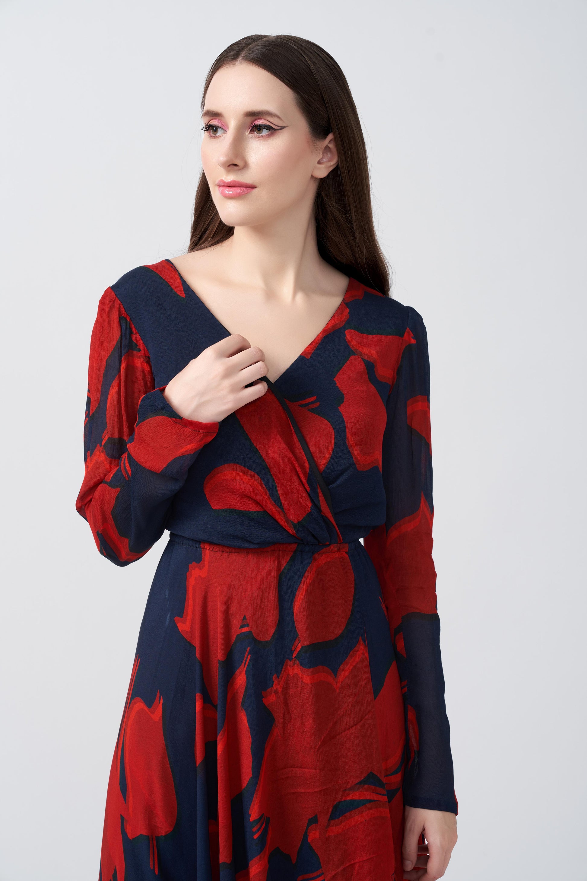 Close-up front view of model wearing red and navy abstract chinon dress with V-neckline.