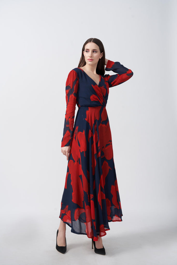 Front-facing view of model in red and navy abstract print ankle-length chinon dress with overlapped V-neck.