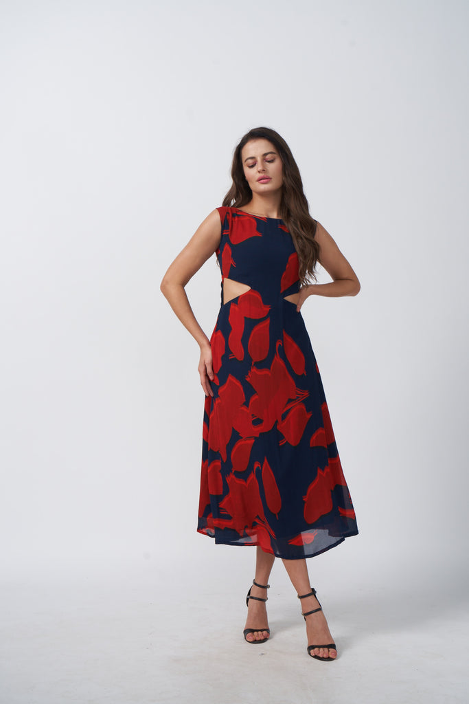 Model posing front-facing in a red and navy abstract floral sleeveless midi dress with waist cutouts.