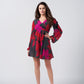 Model wearing a short chinon dress with red and pink abstract floral print, V-neck, and long puff sleeves.