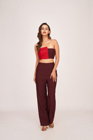 Full-length ensemble featuring a strapless bandeau top with a bold red panel paired with high-waisted dark brown trousers. The Crimson Mocha Co-Ord Set creates a sleek, modern silhouette.