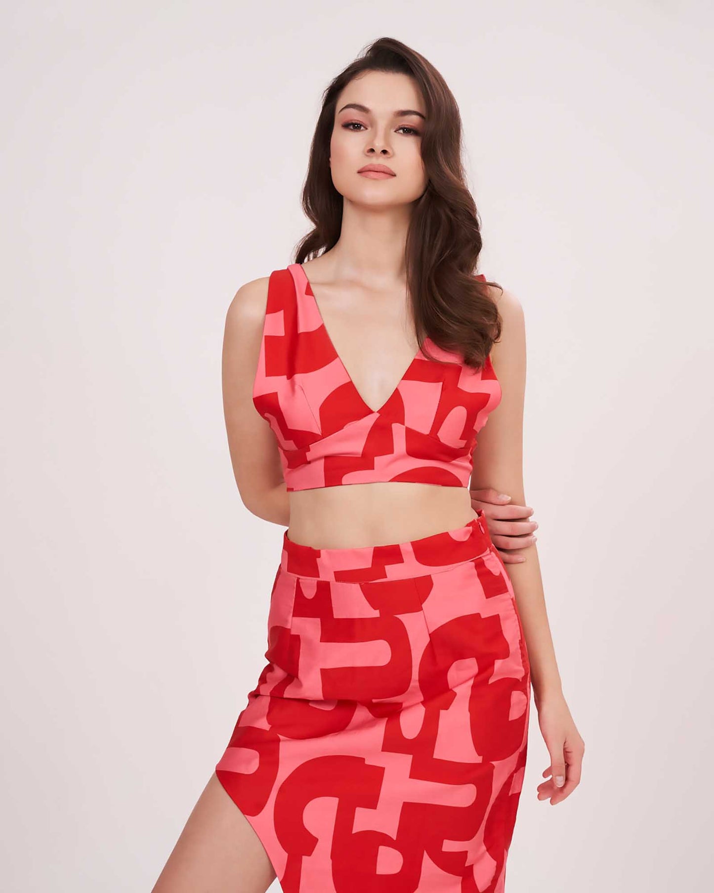 Model in a front-facing pose wearing the deep V-neck red printed co-ord set with sleeveless crop top and high-slit skirt.