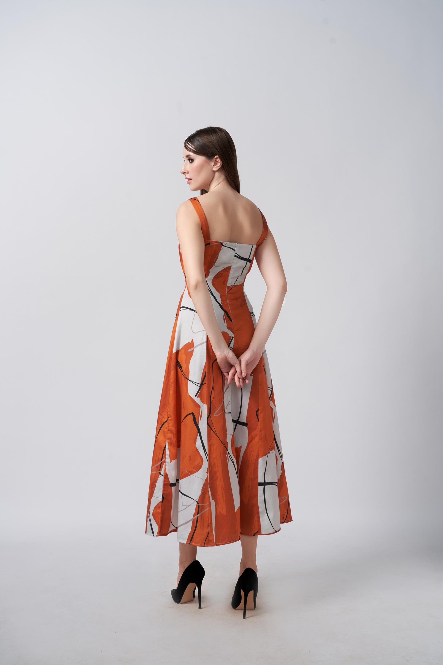 Back view of a burnt orange and white abstract print cotton satin midi dress with a flowing drape