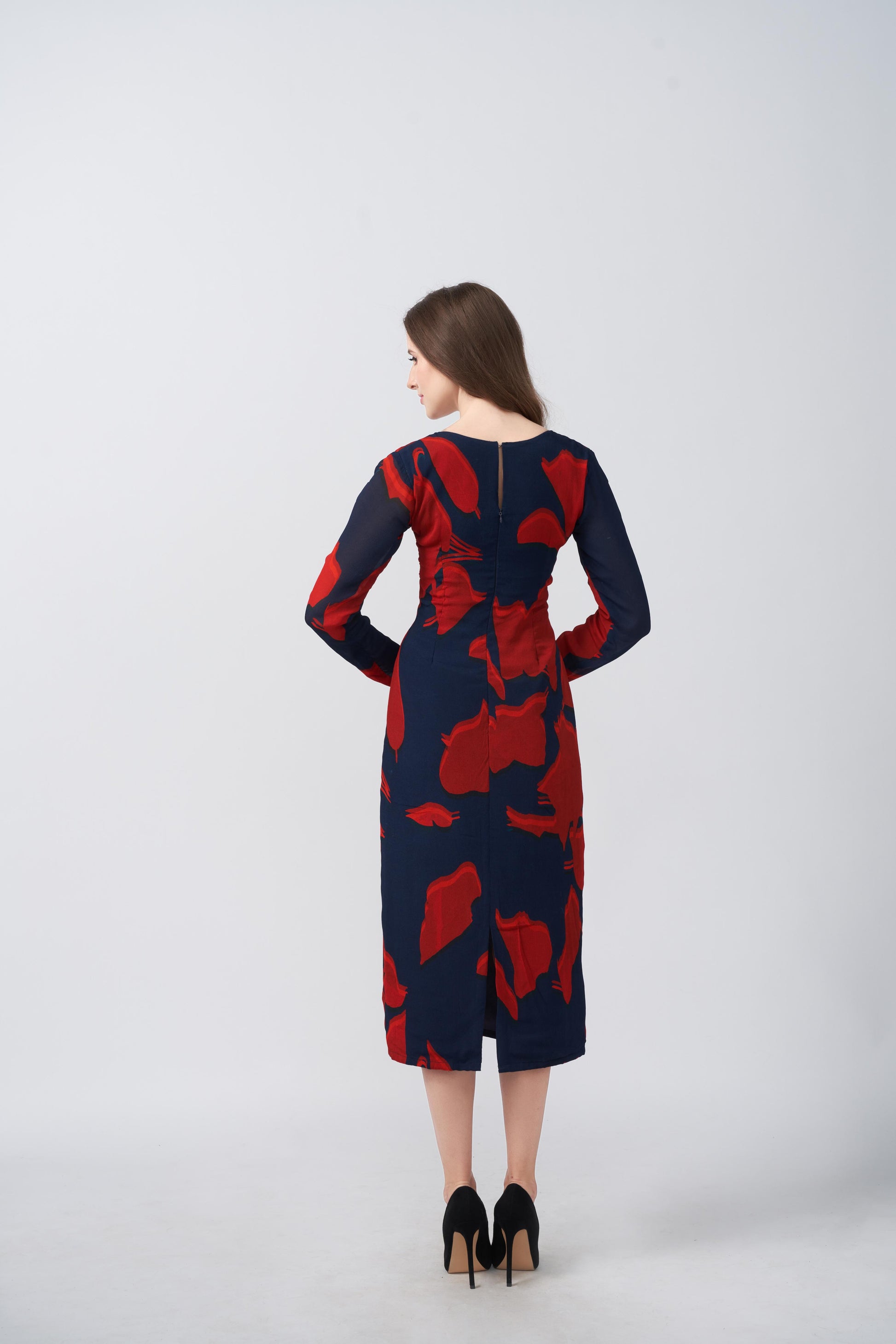 Back view of a red and navy abstract floral midi dress with long sleeves and a fluid drape