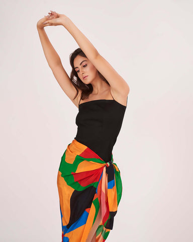 Close-up of the side knot detail that defines the waist and secures the flowy wrap skirt. The Sexy Sarong Dress features a striking mix of primary colors against a black base.
