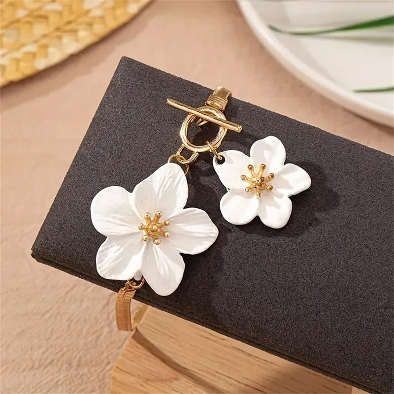 This elegant gold-toned anklet with its row of blooming white blossoms offers a timeless look, designed to elevate your summer vacation wardrobe or high-end resort wear.