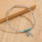 A vibrant turquoise seed bead anklet featuring a delicate gold-toned leaf charm.