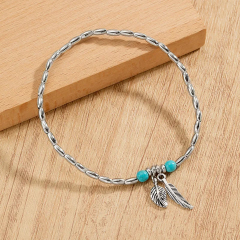 A vibrant turquoise seed bead anklet featuring a delicate gold-toned leaf charm.