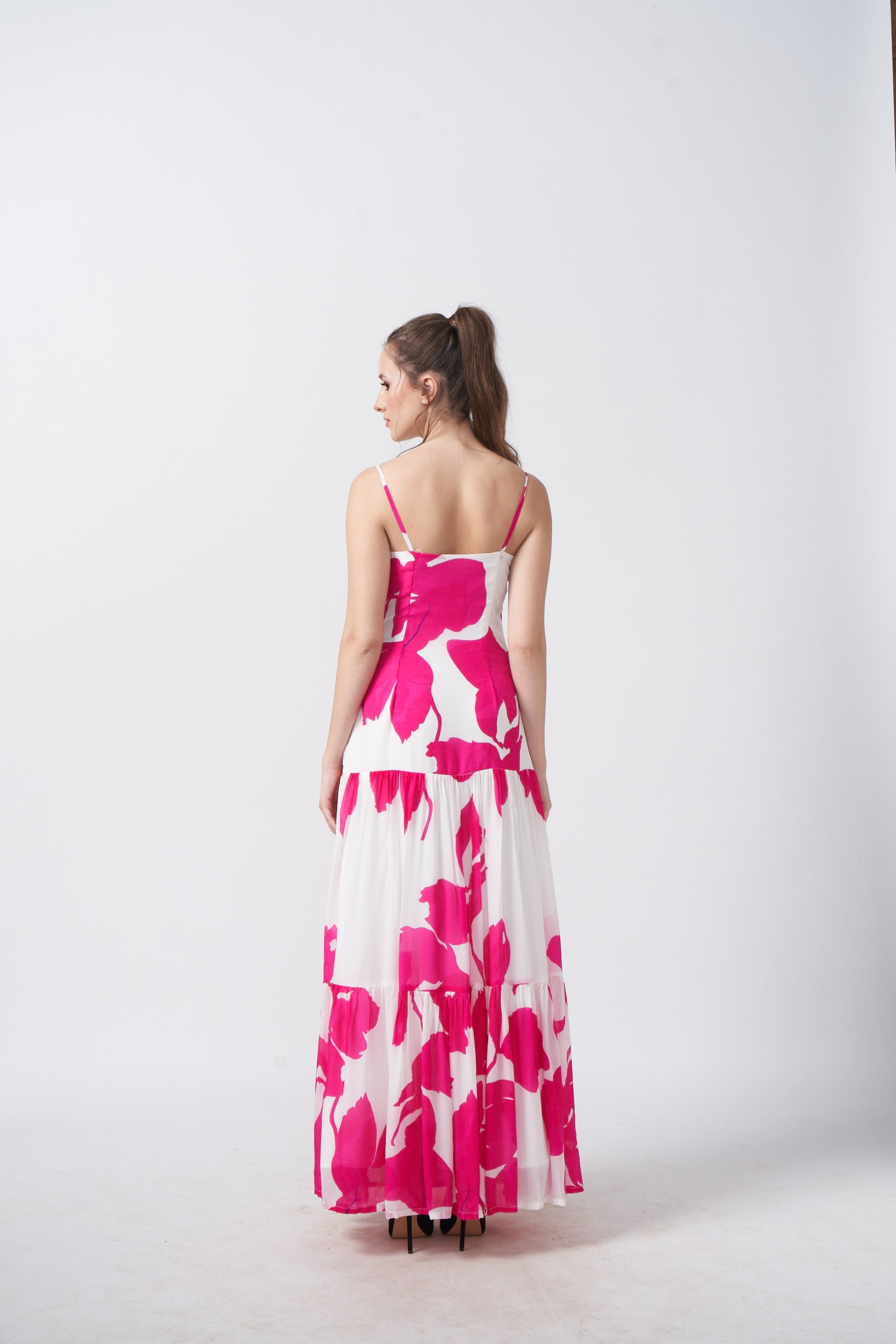 Rear view of the full-length floral dress with spaghetti straps and flowing hemline.