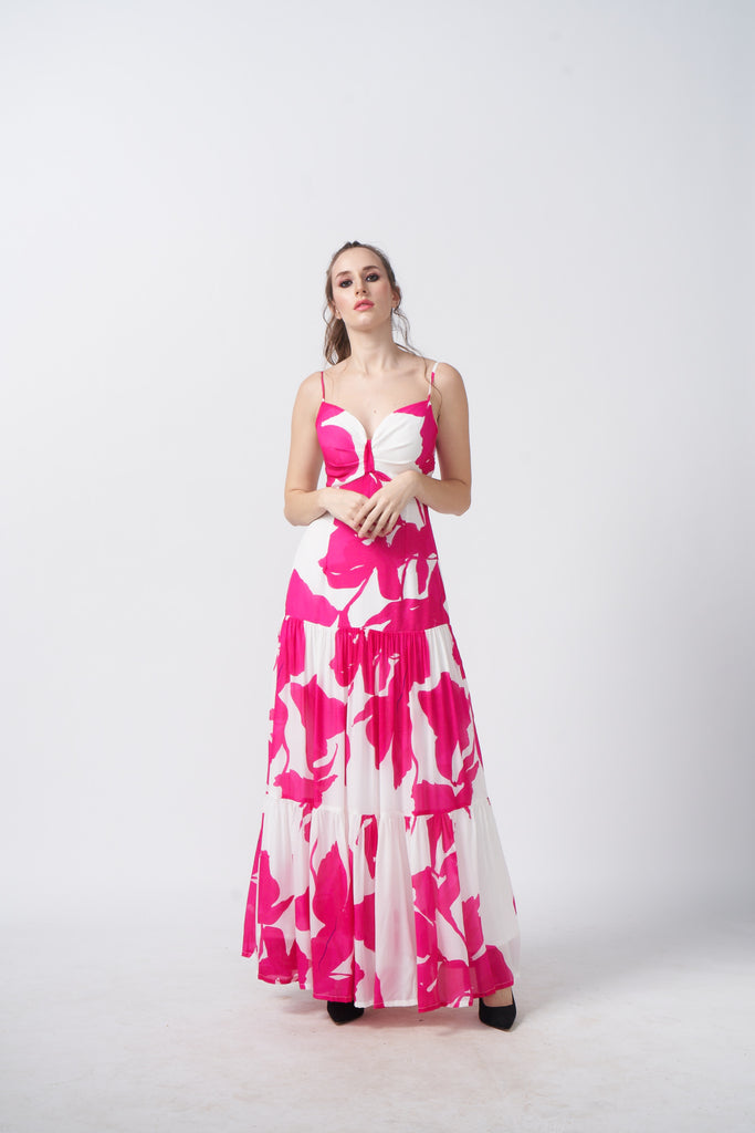 Model standing front-facing in a full-length pink and white floral dress with ruched front and spaghetti straps.