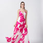 Walking pose of model in the ruched pink and white floral long dress.
