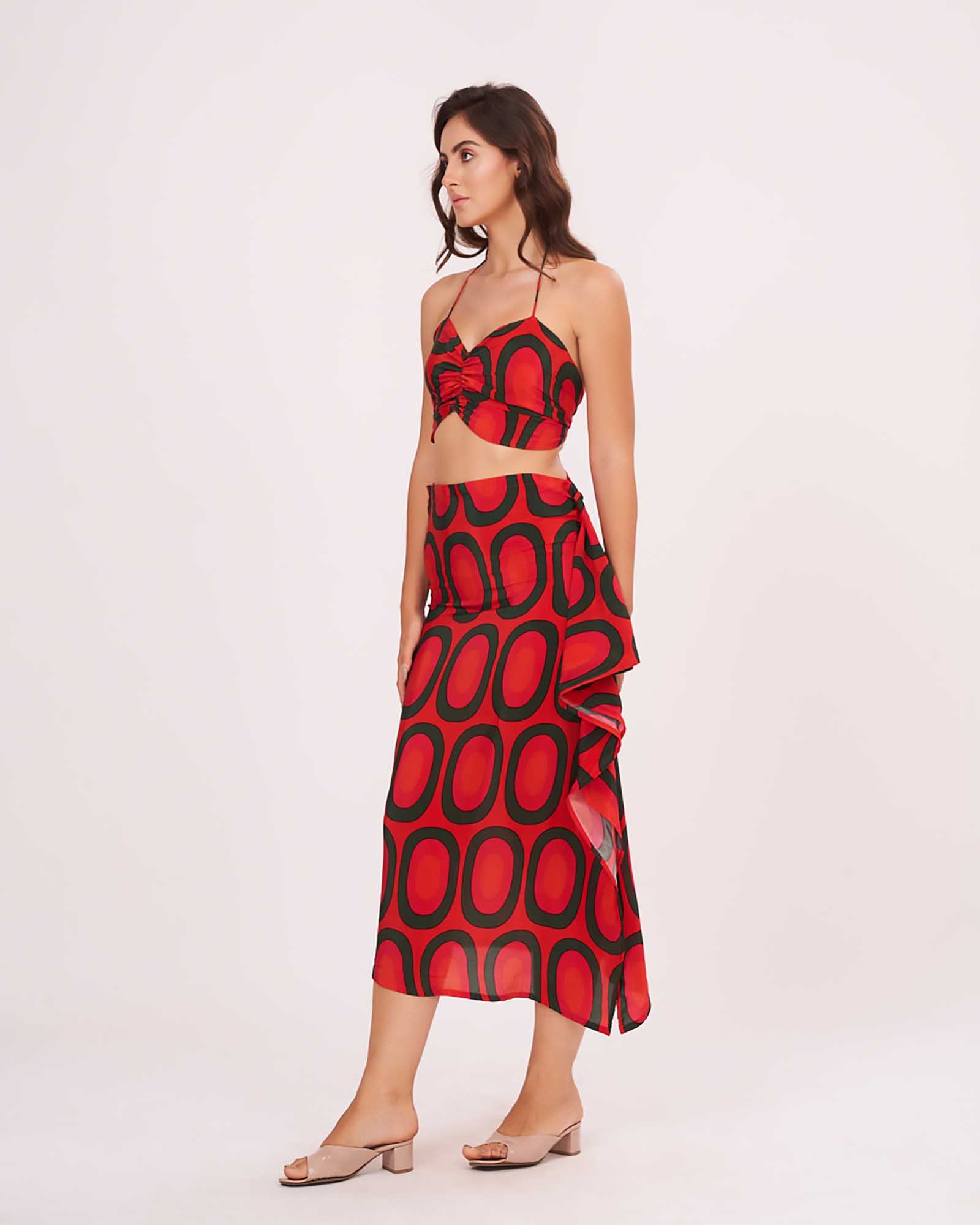 Model stepping forward with a subtle smile, displaying the ruched front crop top and bold abstract skirt print.