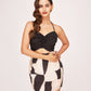 Model with hands on waist in black silk mini dress featuring sweetheart neckline and fitted ruched bodice.