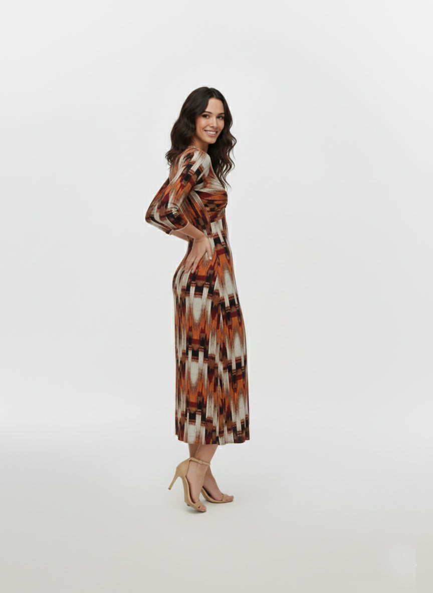 Midi-length Chinon dress with a deep V-neckline, gathered bust detail, ruched waist, three-quarter sleeves, front slit, and abstract ikat-inspired print in saffron, rust, ivory, and brown.