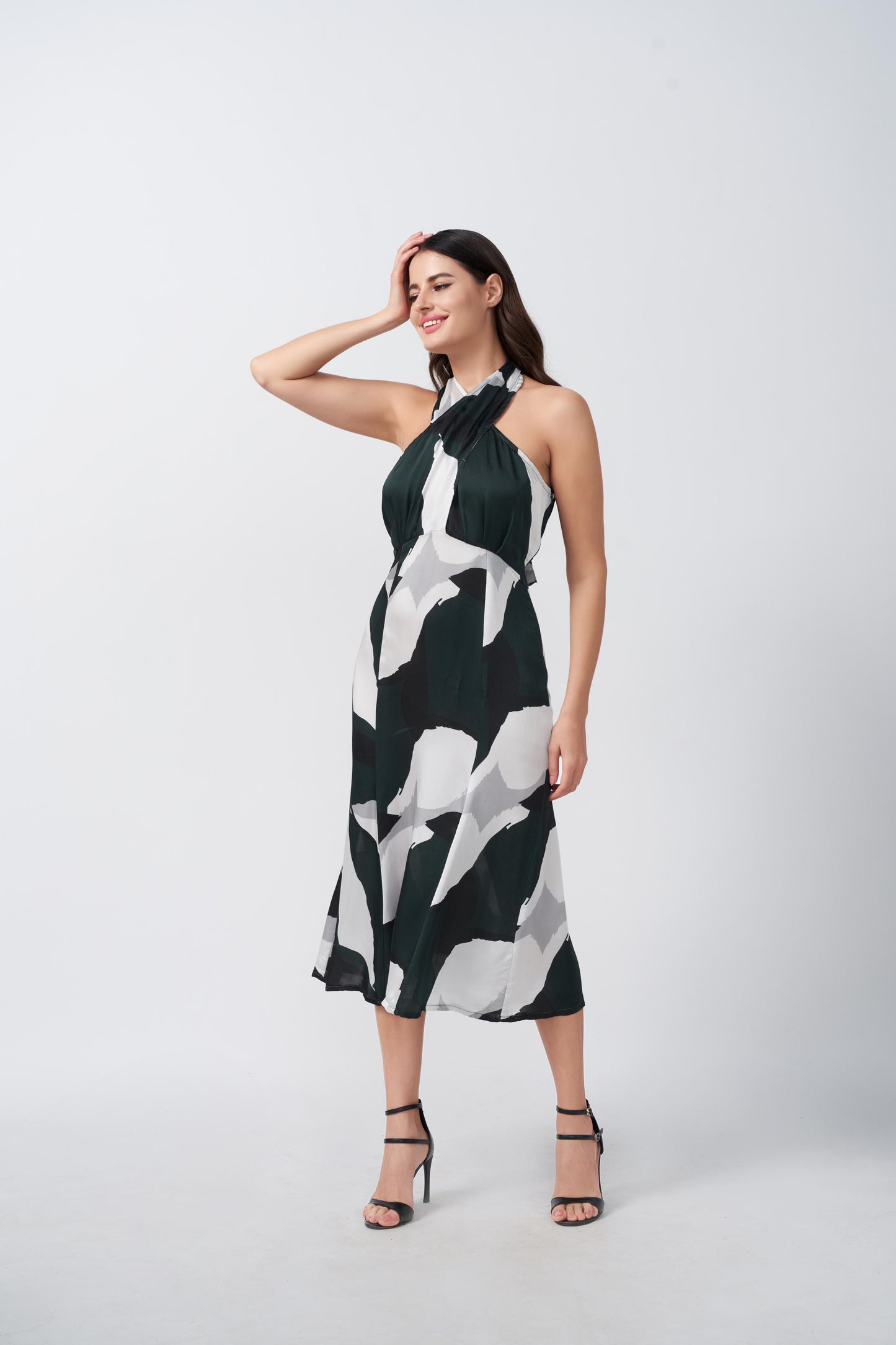 Walking pose of model highlighting the fluidity of the abstract print satin midi dress.