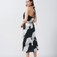 Side profile of model showing halter tie-back neck and silhouette of satin abstract print dress.