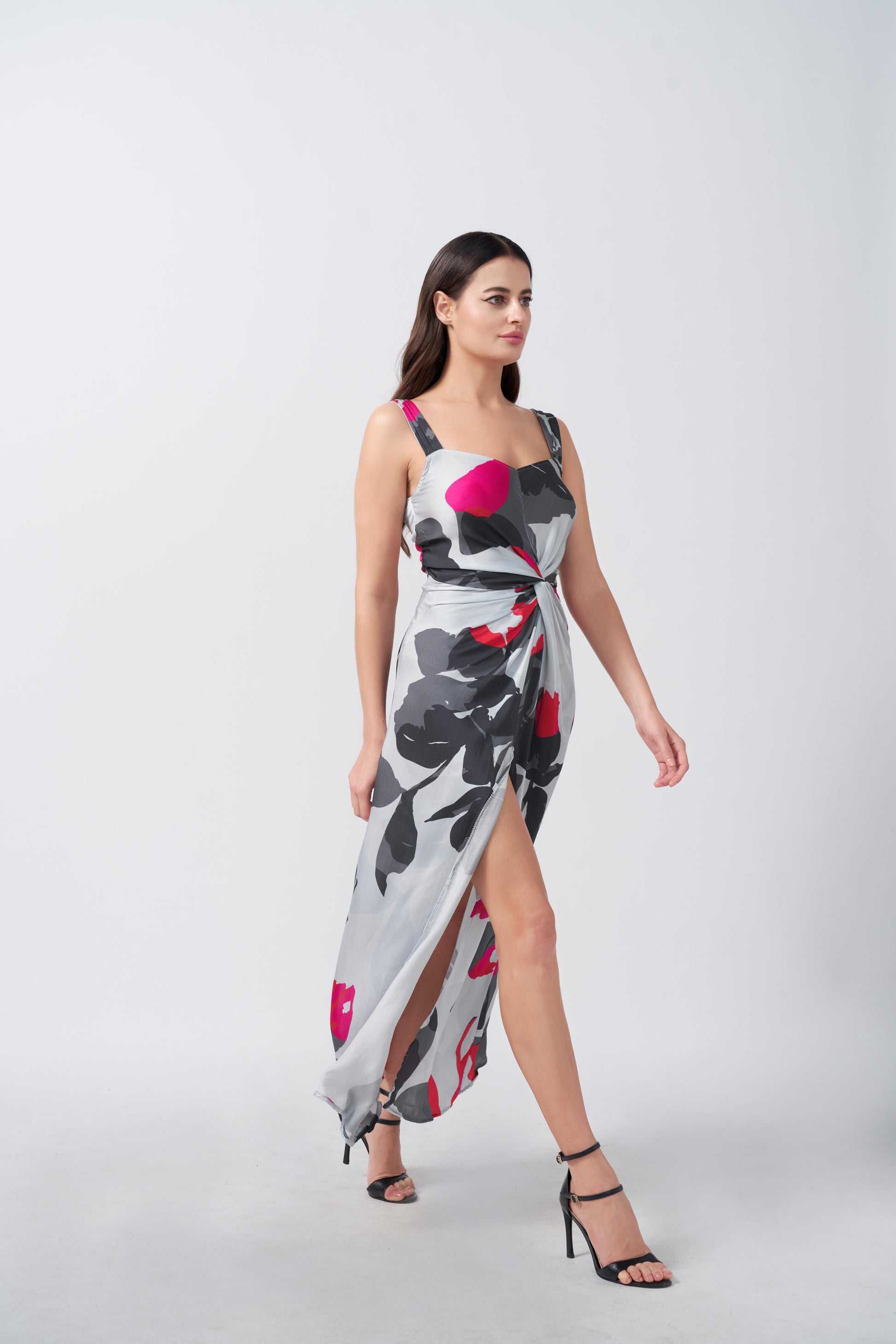 Walking pose of model highlighting front slit and movement of grey and white satin dress.