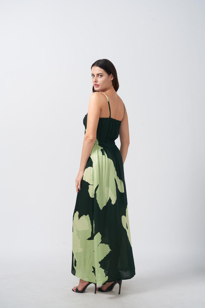 Rear view of model in light and dark green floral satin dress with spaghetti straps.
