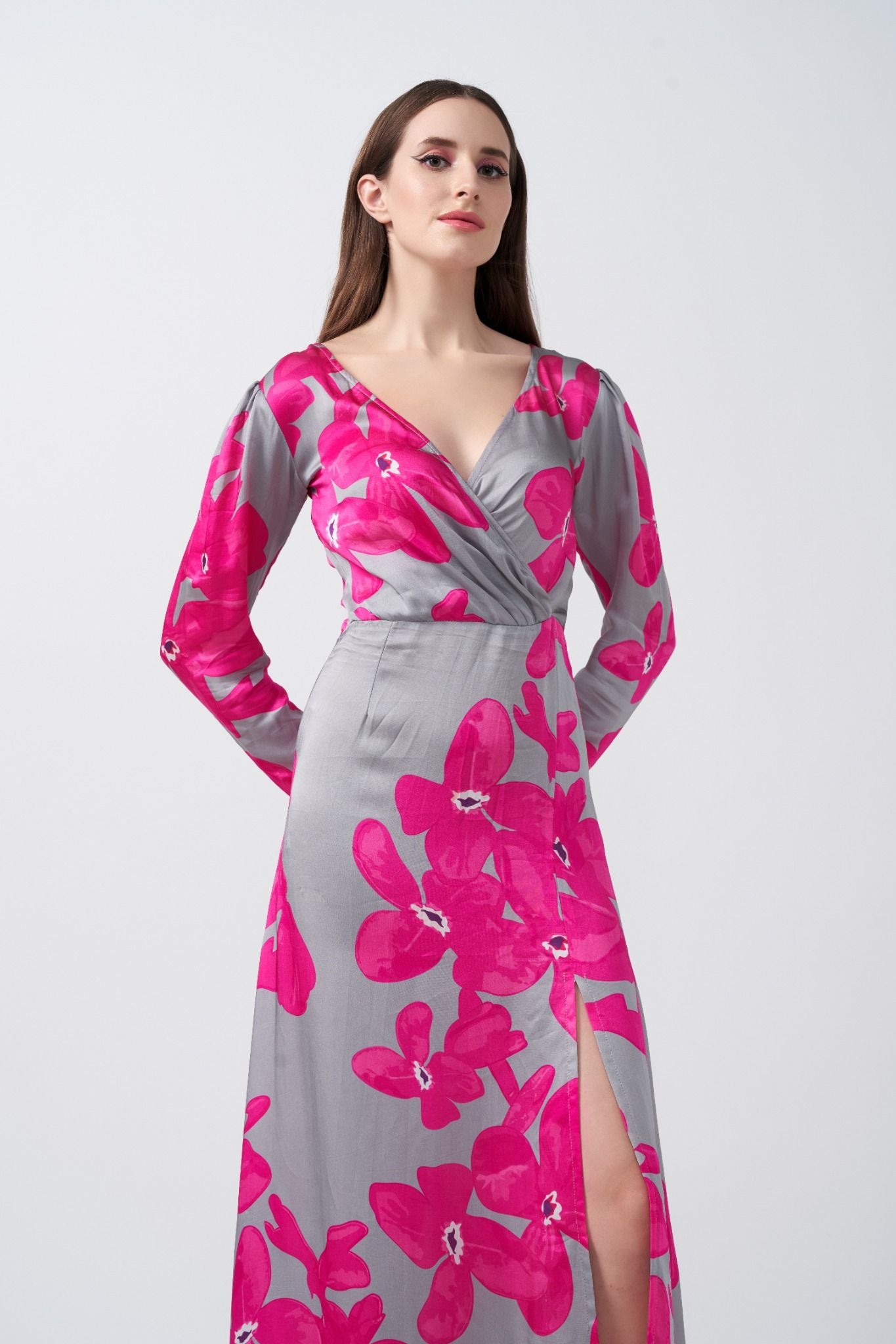 Front view of the model in a satin pink and grey floral dress with overlapped V-neck and elegant full sleeves.