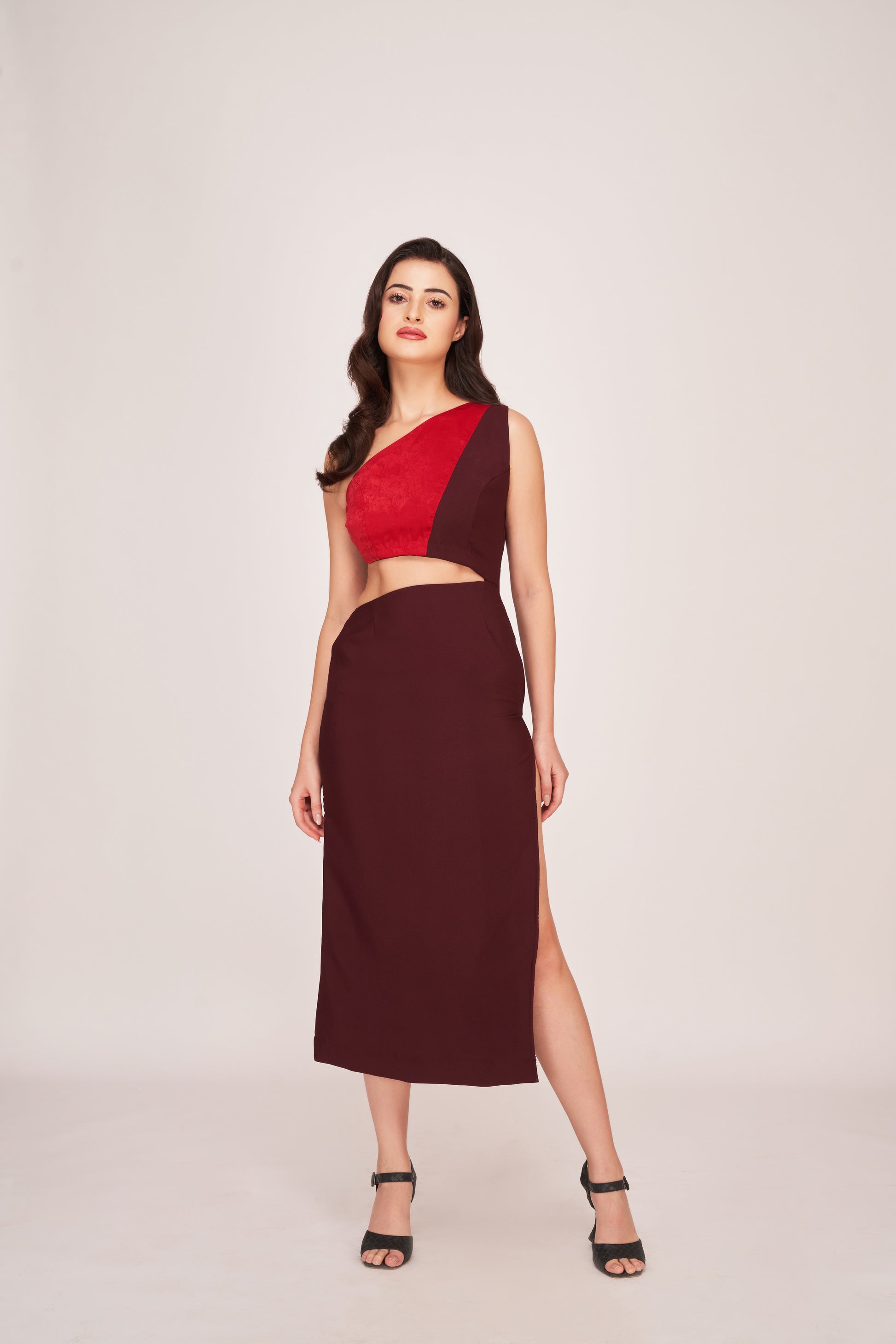 Model walking forward in red and brown crepe panelled dress, showing high slit and body-hugging fit.