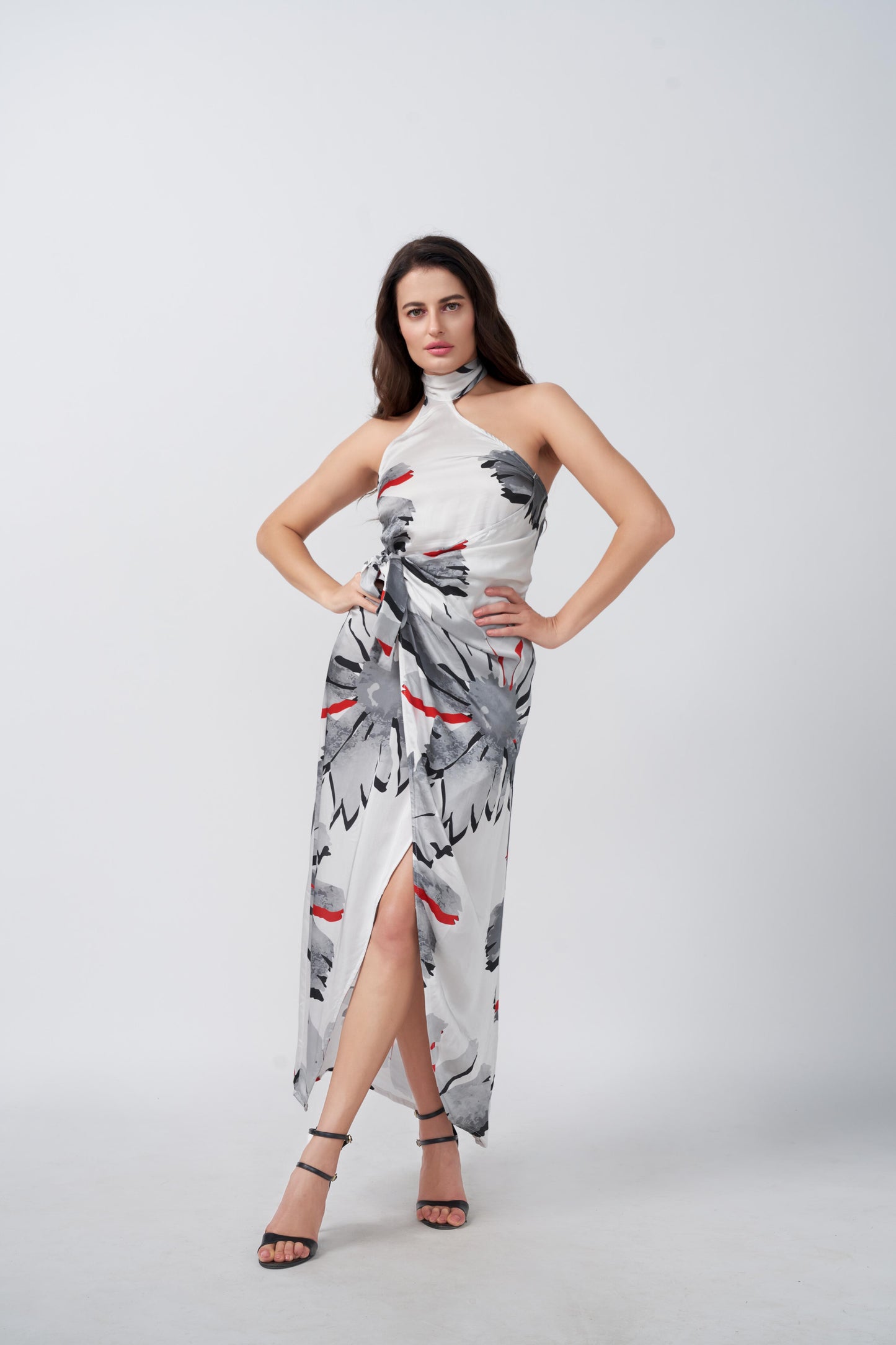 Model posing with hands on waist in grey and red floral halter neck satin dress with wrap style.