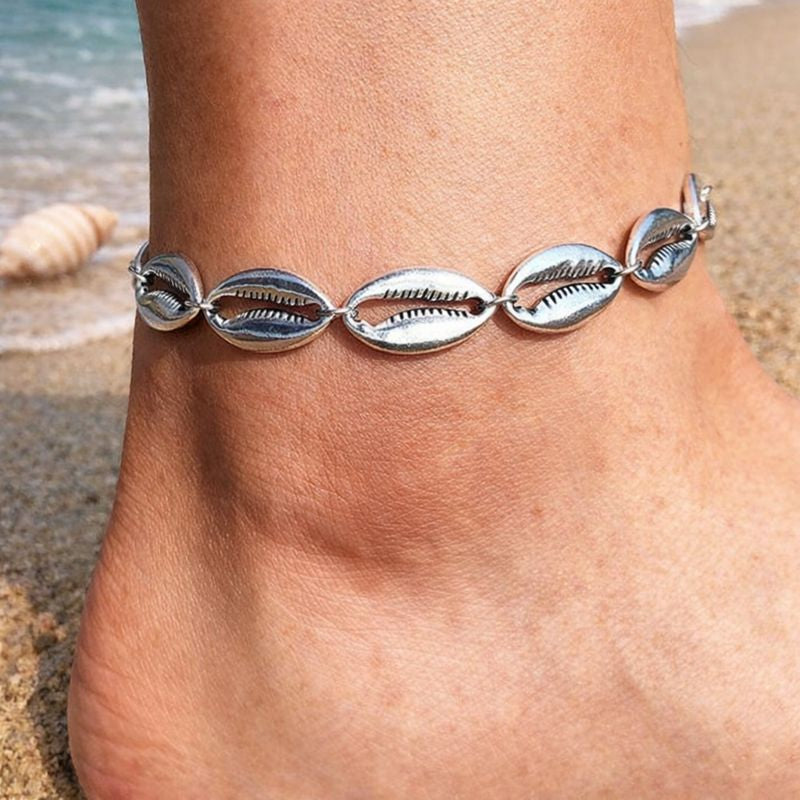 A bright sterling silver anklet featuring detailed, high-shine cowrie shell charms, perfect for adding a polished beachy vibe to your summer evening look.