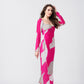 Woman in a pink and white abstract print ankle-length dress, captured in a side profile pose.
