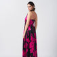 Side angle of model wearing pink and black gathered flare satin dress with ankle-length hem and soft flow.