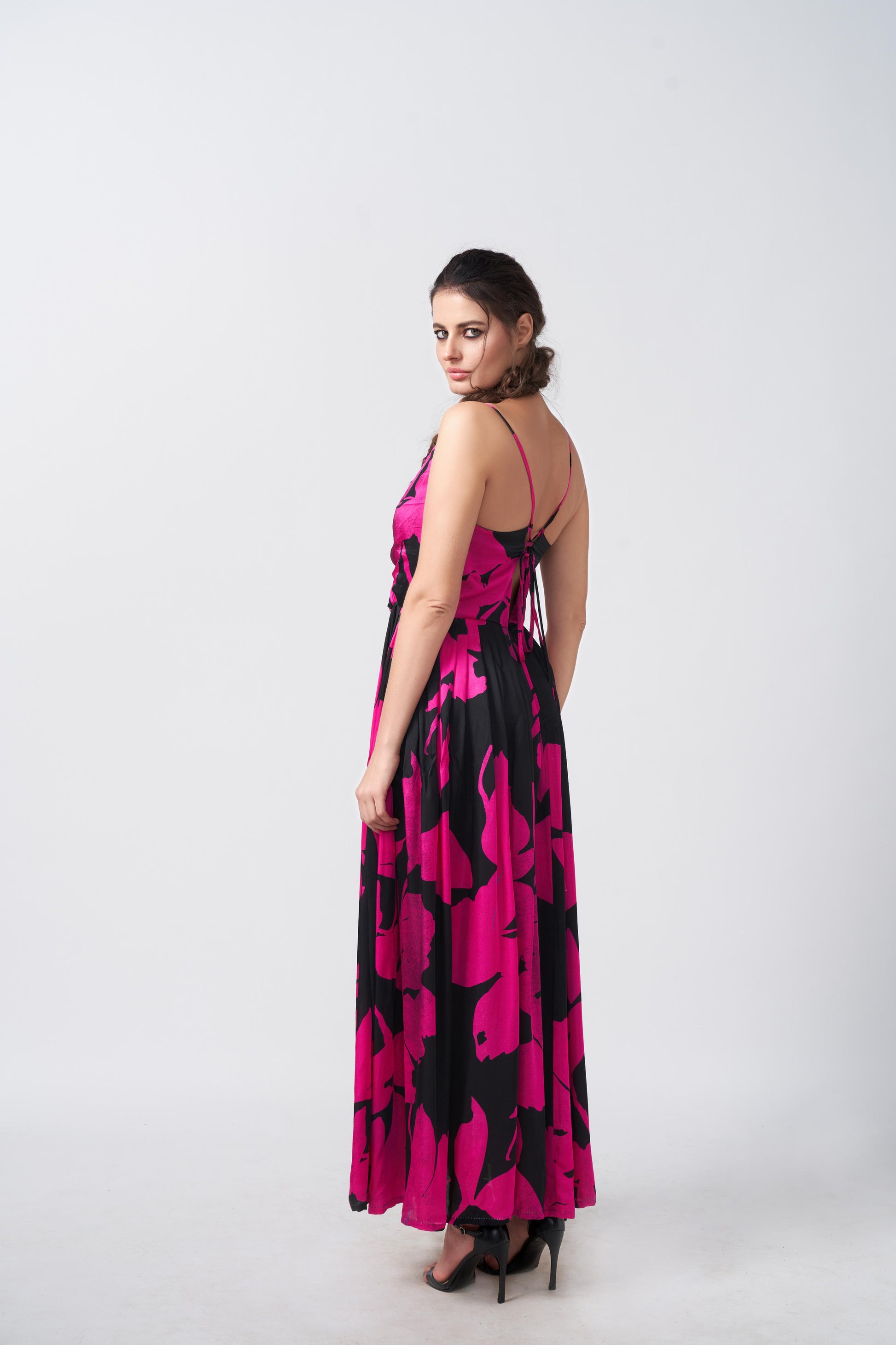 Side angle of model wearing pink and black gathered flare satin dress with ankle-length hem and soft flow.