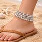 A stylish set of stacked silver-toned seed bead anklets in a mix of metallic and iridescent finishes, perfect for adding a subtle sparkle to your casual weekend outfits or a day at the beach.