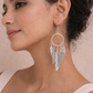 A woman wearing bohemian silver Feather Hoop Drop Earrings featuring a circular hoop with multiple dangling metallic feather charms.