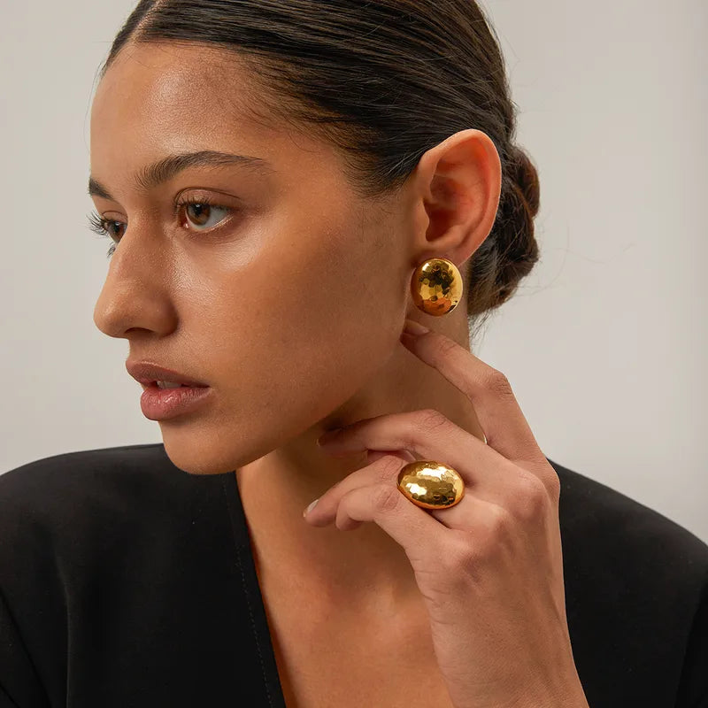 These sleek gold-toned oval studs offer a minimalist and sophisticated look that sits comfortably on the ear, making them an ideal accessory for a chic lunch date or a refined evening event.