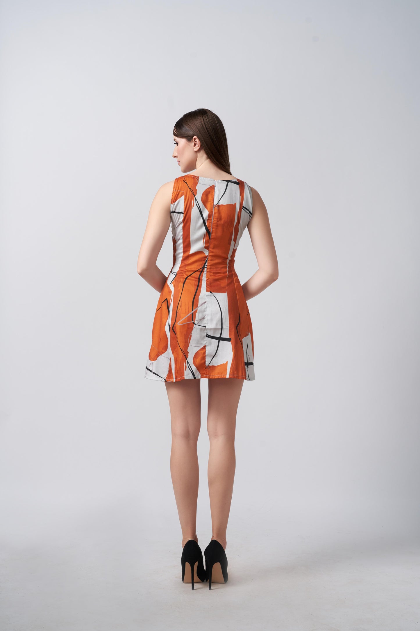 Backview of a model in bold burnt orange and white sleeveless short dress, showing clean lines and tailored fit.