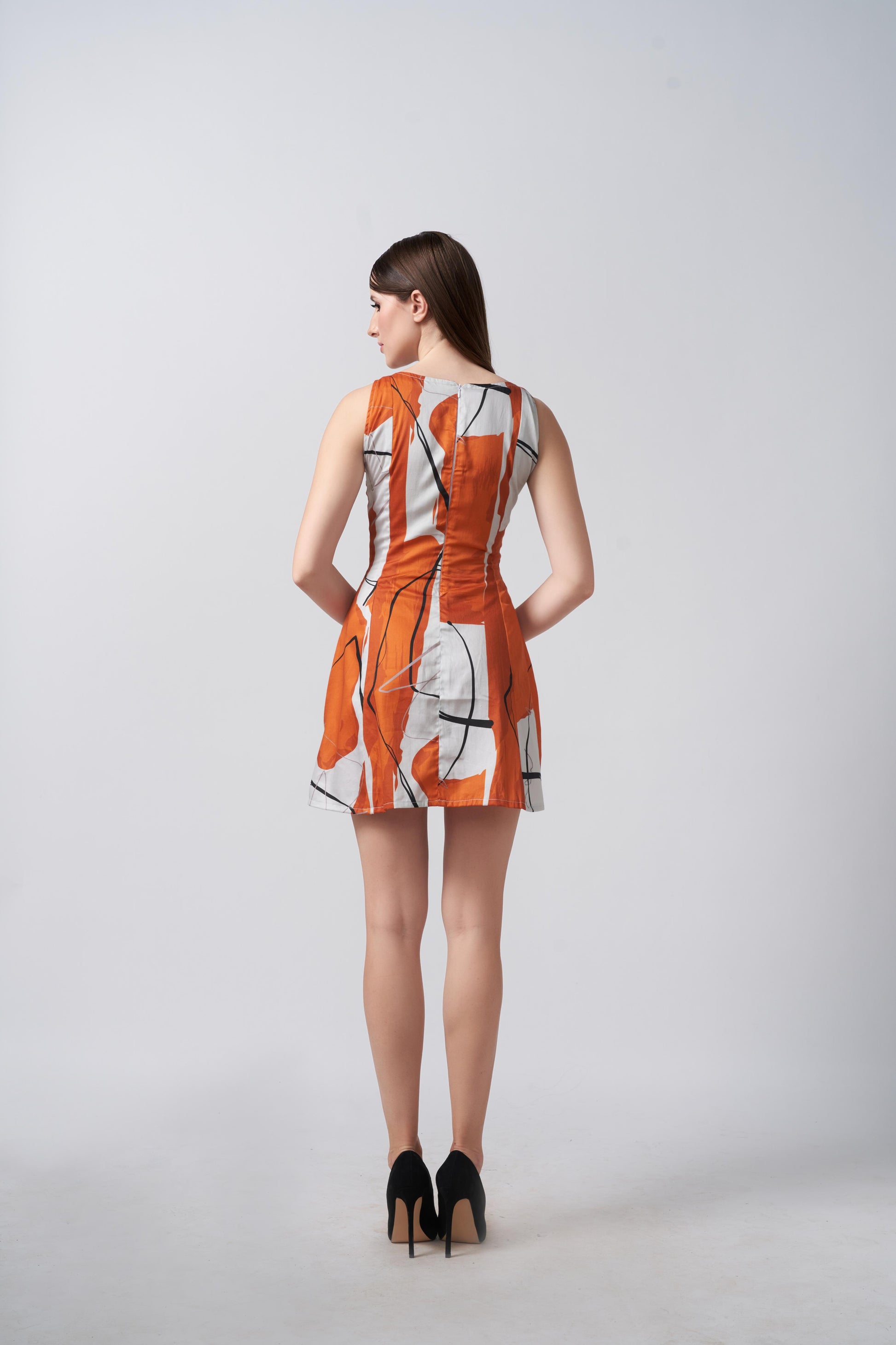 Backview of a model in bold burnt orange and white sleeveless short dress, showing clean lines and tailored fit.