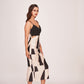 Angled walking pose of model in printed satin dress showing side profile, pleated yoke, and fluid silhouette.