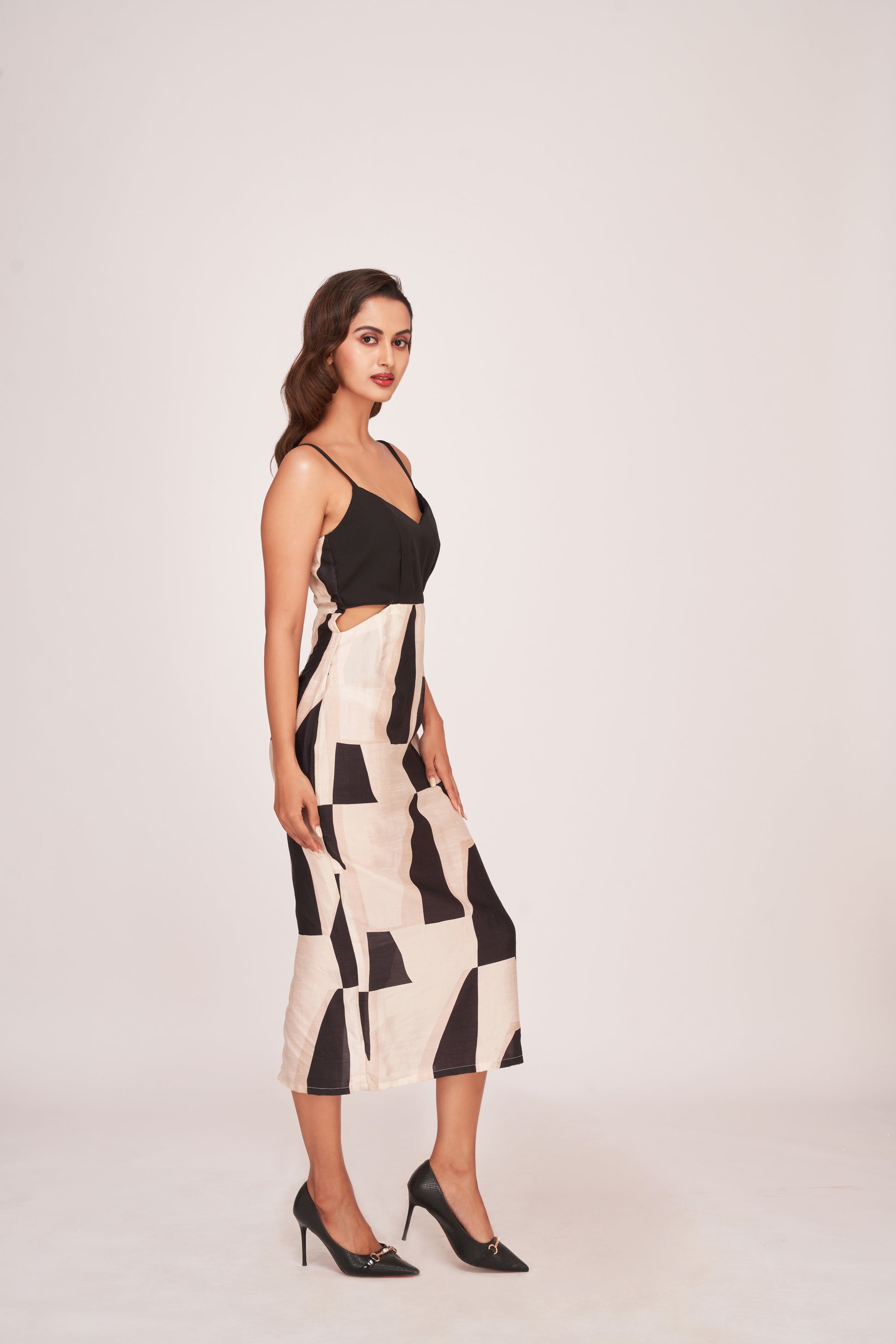 Angled walking pose of model in printed satin dress showing side profile, pleated yoke, and fluid silhouette.
