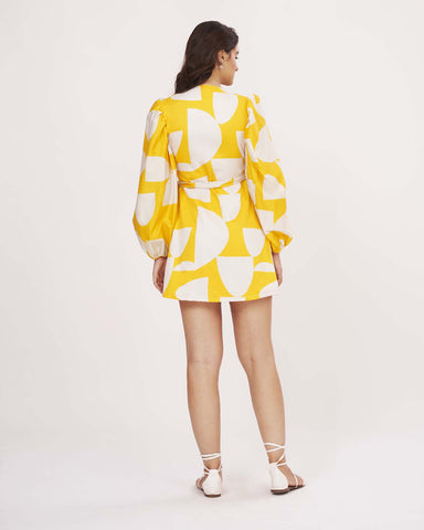 Back view of yellow abstract wrap dress with tie-up detail and full balloon sleeves.