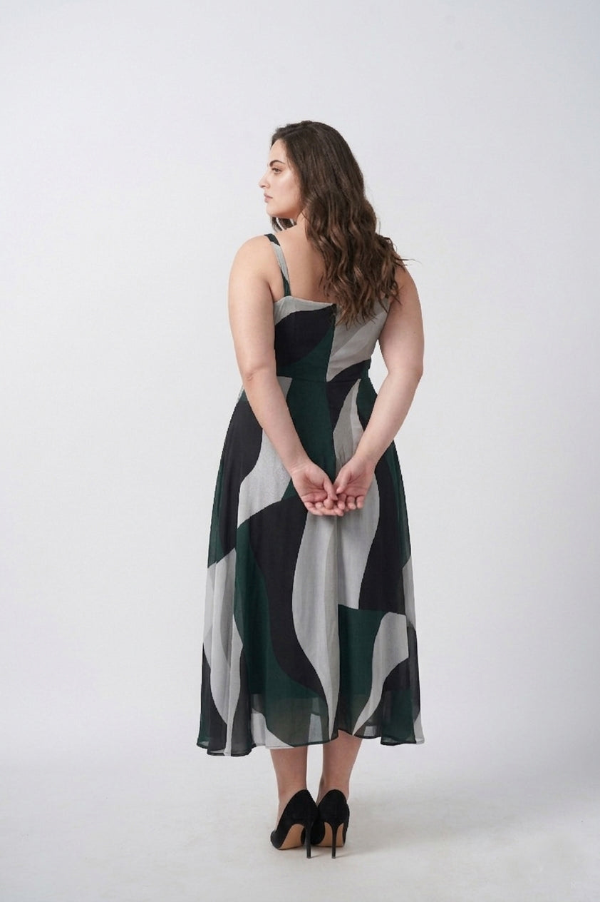 Close-up of delicate shoulder straps and neckline on a green abstract print crepe midi dress