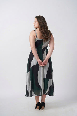 Close-up of delicate shoulder straps and neckline on a green abstract print crepe midi dress