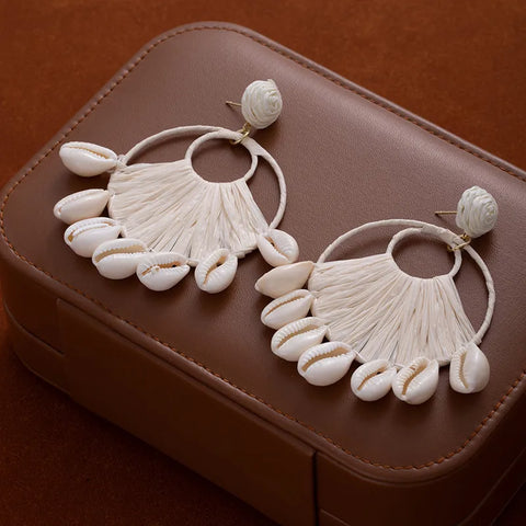 A beautiful blend of coastal and bohemian styles, these white raffia shell drop earrings offer a breezy, high-fashion look designed to elevate your favorite sundress or a chic linen outfit.
