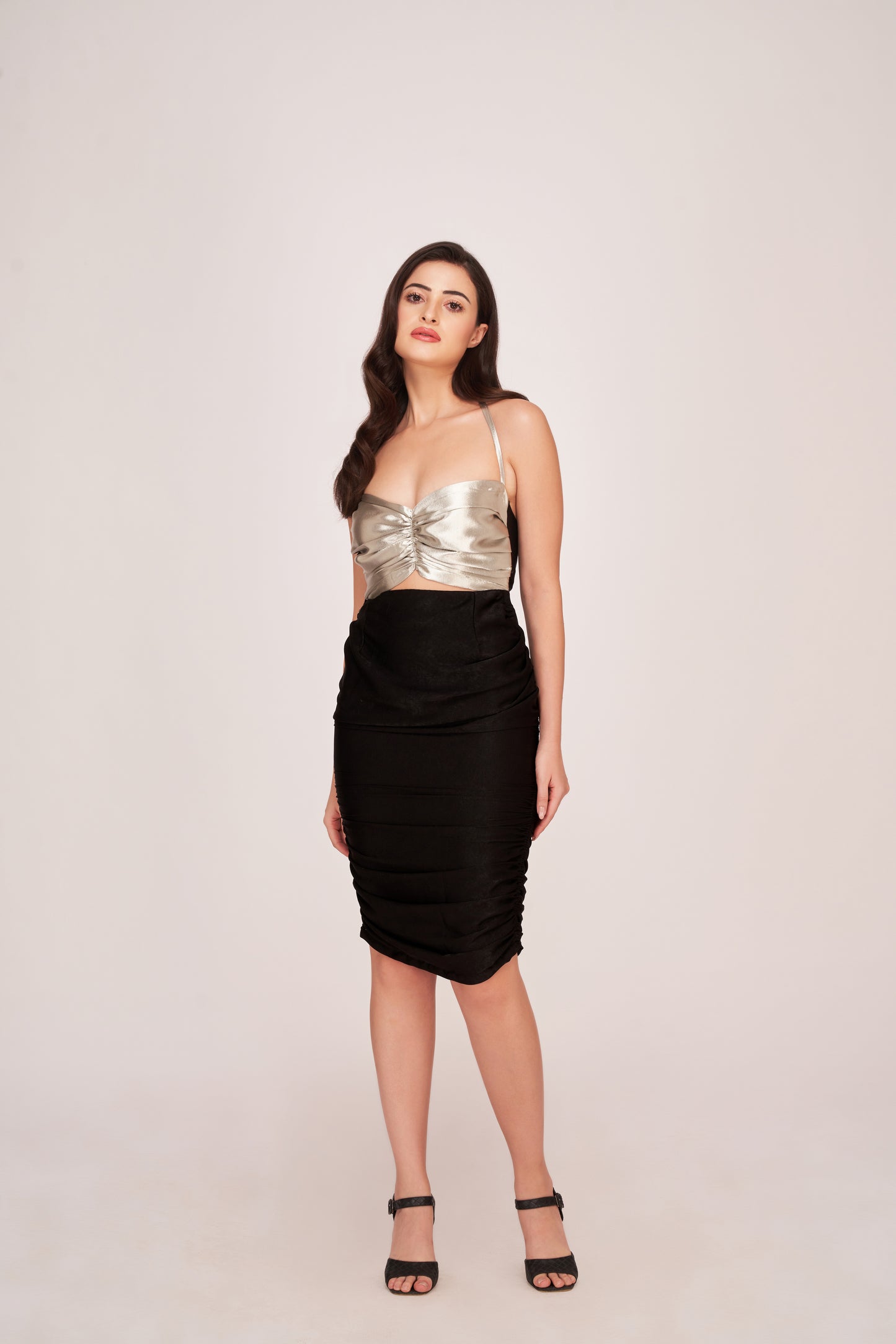 Angled pose of model smiling in silver and black sweetheart neck dress with flattering ruched finish.