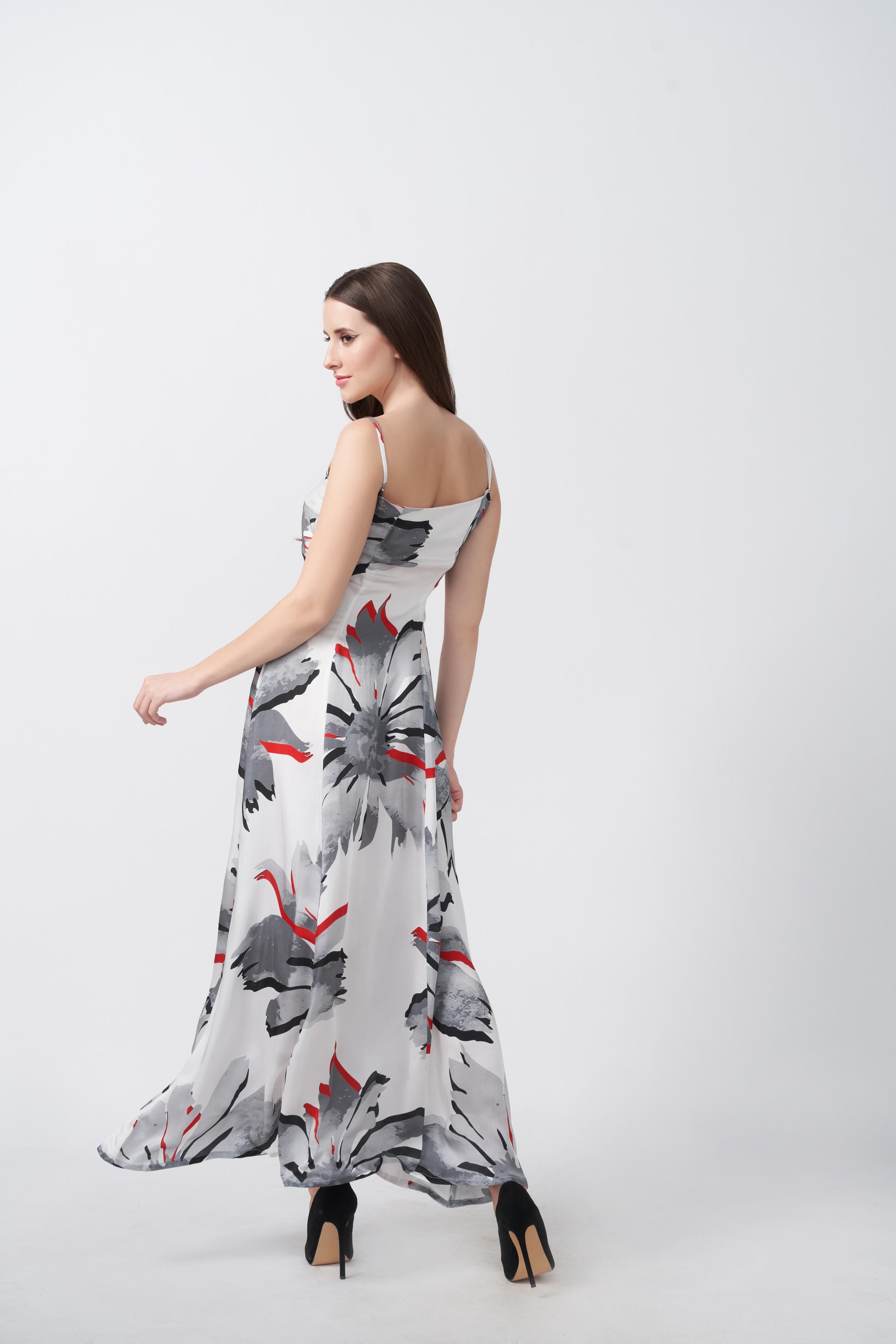 Side view of model walking in elegant satin floral dress with spaghetti straps and modern silhouette.