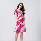 Side view of model in pink and white abstract mini dress with puff sleeves and modern twisted neckline.