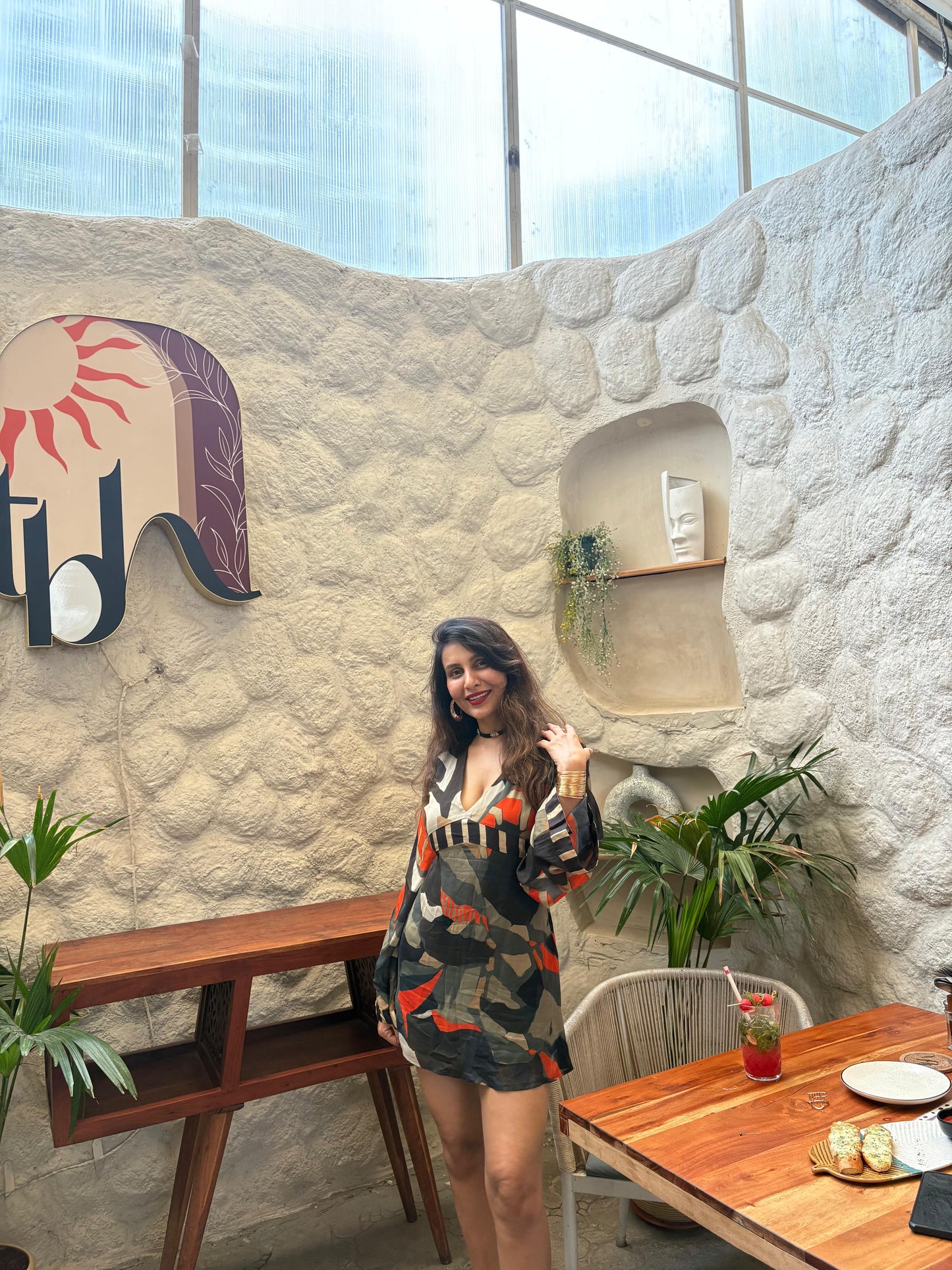 Mini dress with a deep V-neckline, long billowing sleeves, and a multicolored abstract print in earthy and vibrant tones