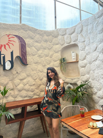 Mini dress with a deep V-neckline, long billowing sleeves, and a multicolored abstract print in earthy and vibrant tones