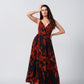 Model posing front-facing in the red and pink abstract floral gathered flare dress with one hand raised